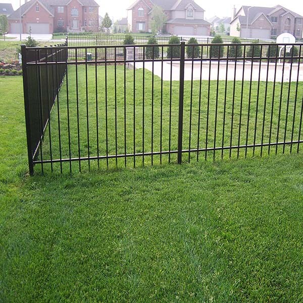 A black fence surrounds a grassy yard with trees in the background in Batavia, IL