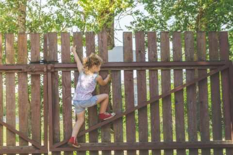 The small kid playing with wooden fence wall