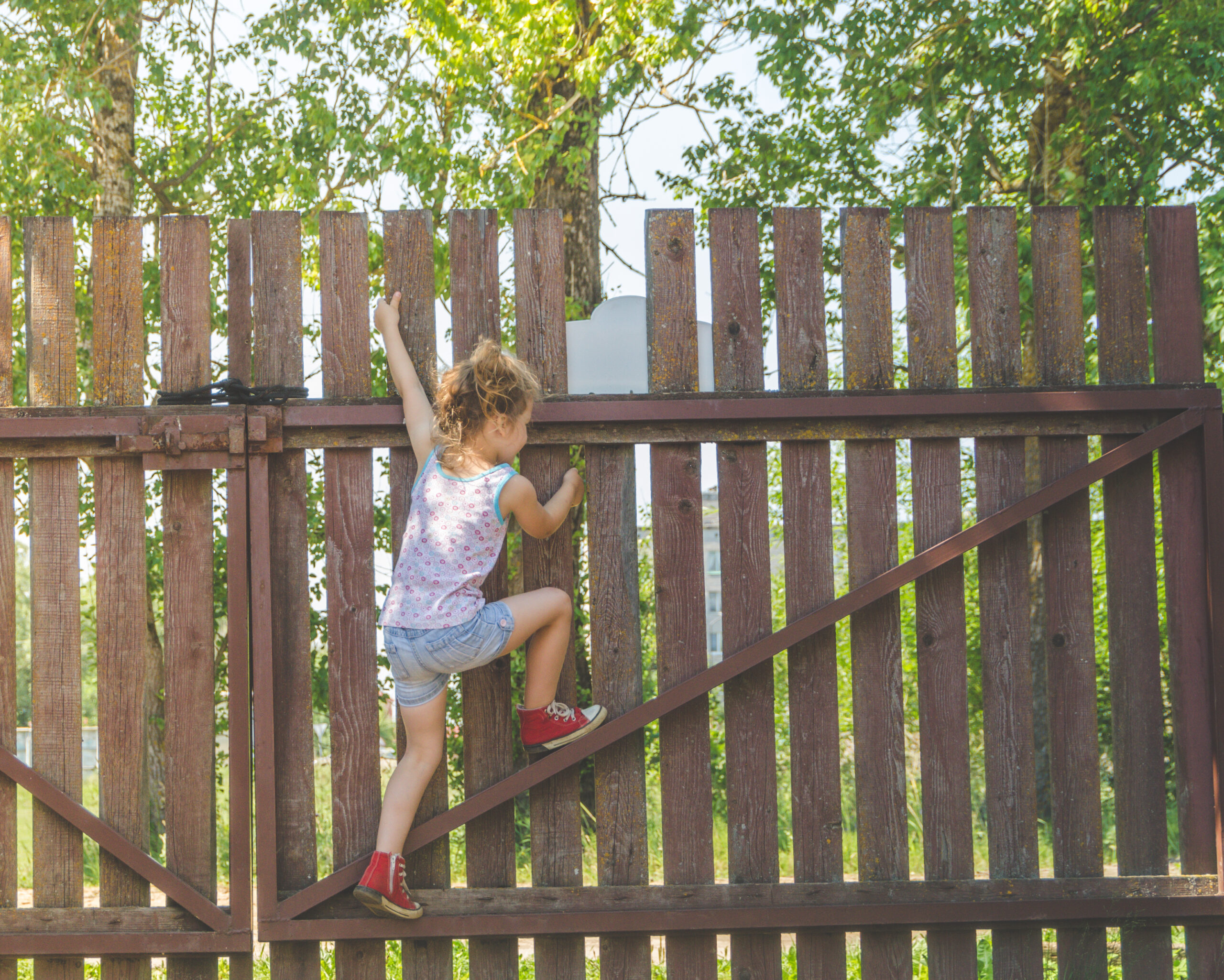 girl climbs the fence on a summer day