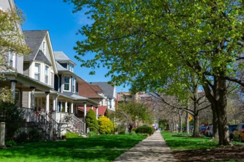 A row of old wooden homes with front lawns and a sidewalk in the North Center neighborhood of Chicago, IL