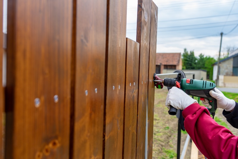 Man building a special wooden fence with driller in Chicago, IL