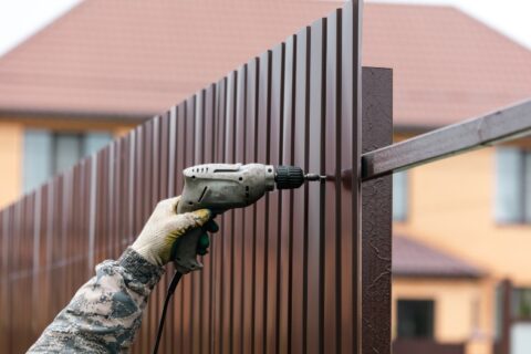 Workers install a metal profile fence in Chicago, IL