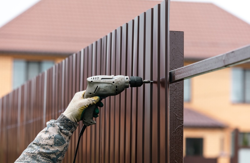 Workers install a metal profile fence in Chicago, IL