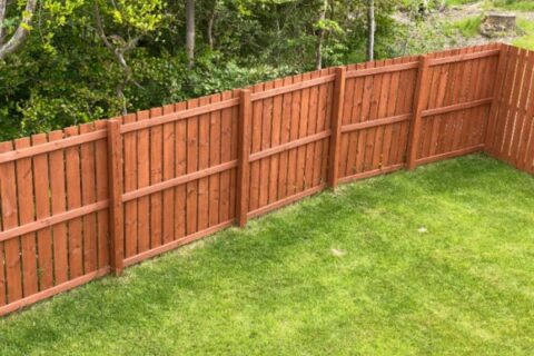 Wooden garden fence coated with medium oak stain in Chicago, IL
